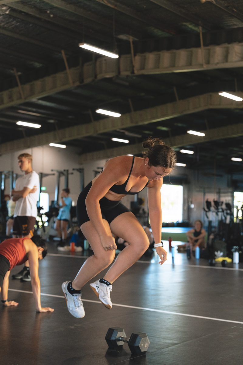 Athlete mid-air during a high-intensity dumbbell workout